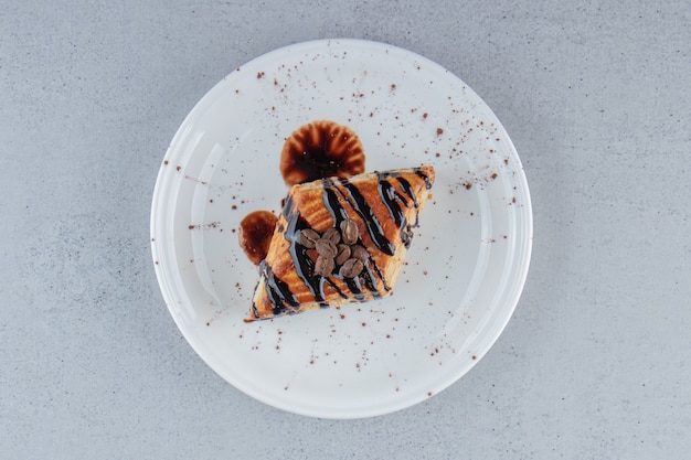 Pâtisserie sucrée décorée de chocolat placé sur une assiette blanche