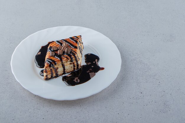 Pâtisserie sucrée décorée de sirop de chocolat placé sur une assiette blanche. photo de haute qualité