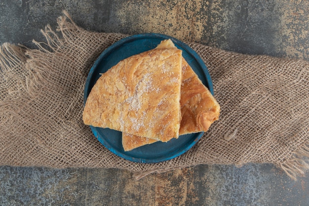 Pâtisserie triangulaire avec du sucre sur une plaque bleue