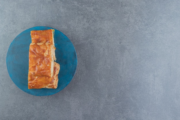 Pâtisseries farcies de forme carrée sur planche bleue.