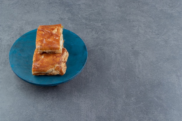 Pâtisseries farcies de forme carrée sur planche bleue.