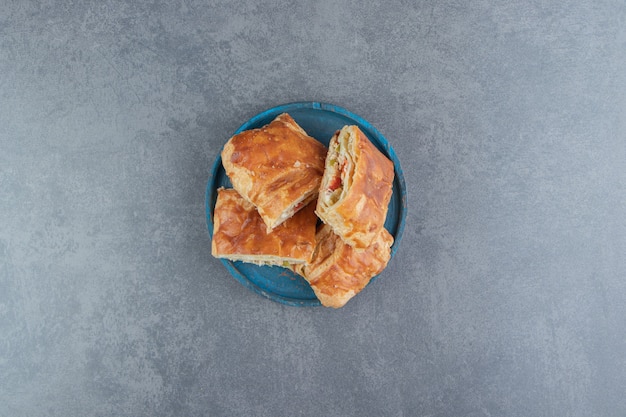 Pâtisseries farcies de forme carrée sur plaque bleue.