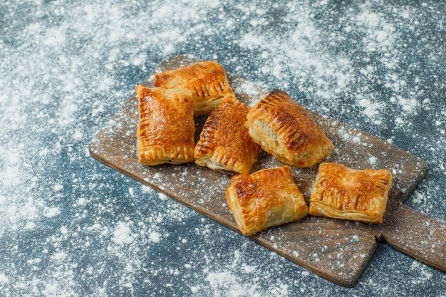 Photo gratuite pâtisseries avec farine saupoudrée sur béton et planche à découper