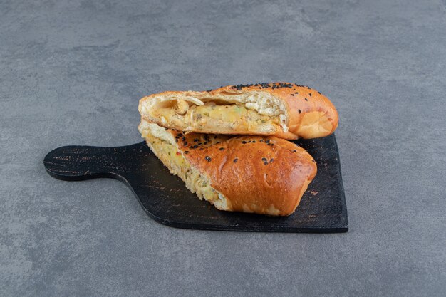 Pâtisseries fraîches à moitié coupées aux graines de sésame sur tableau noir.