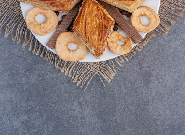 Pâtisseries maison et fruits secs sur plaque blanche.