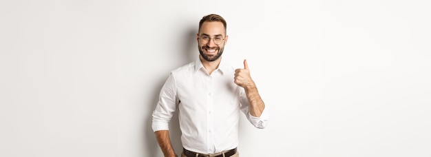 Patron réussi satisfait montrant le pouce vers le haut approuver et louer le bon travail debout sur fond blanc