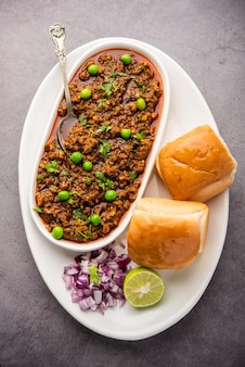 Pavé de mouton kheema ou viande hachée épicée indienne servie avec du pain ou du kulcha, garni de pois verts. fond de mauvaise humeur. mise au point sélective