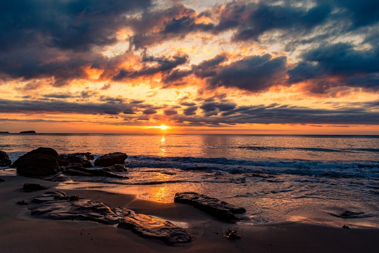 Photo gratuit un paysage à couper le souffle d'une plage de sable sur un magnifique coucher de soleil