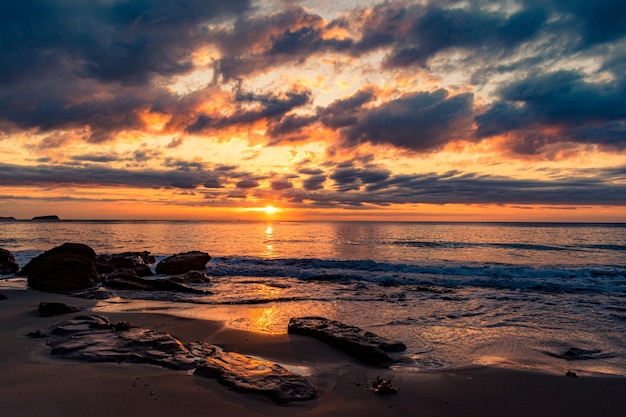 Paysage à couper le souffle d'une plage de sable sur un magnifique coucher de soleil