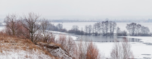 Paysage d'hiver avec rivière, rocher et arbres au bord de la rivière