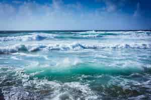 Photo gratuite paysage d'une mer ondulée sous la lumière du soleil et un ciel bleu