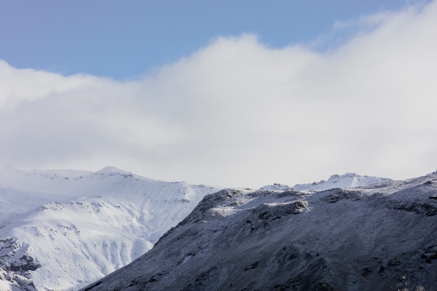 Paysage de montagnes couvertes de neige sous un ciel bleu nuageux en Islande