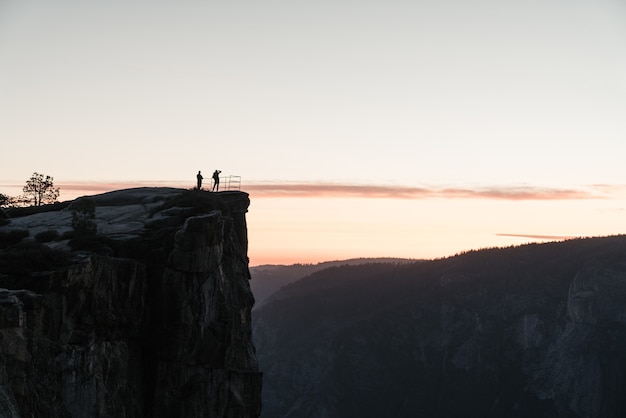 Photo gratuite paysage de personnes debout au sommet d'une formation rocheuse admirant la beauté de la nature