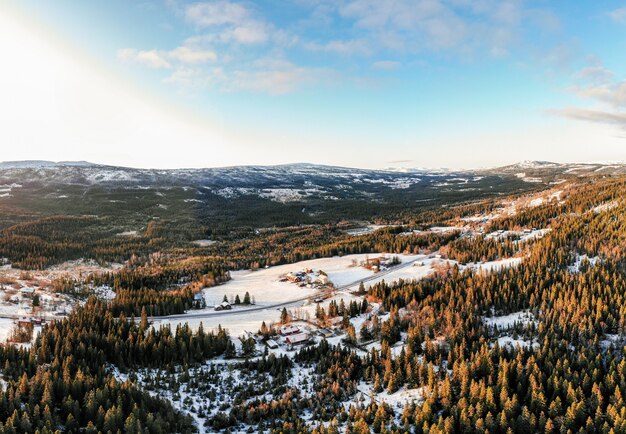 Paysage d'un village entouré de forêts couvertes de neige sous un ciel bleu et la lumière du soleil