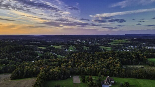 Paysage d'une ville entourée de forêts sous un ciel nuageux au lever du soleil