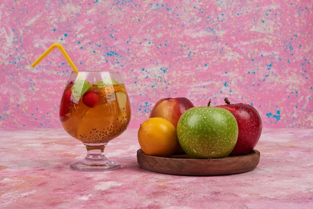 Peach, pommes citronnées avec des tasses de jus sur planche de bois au centre.