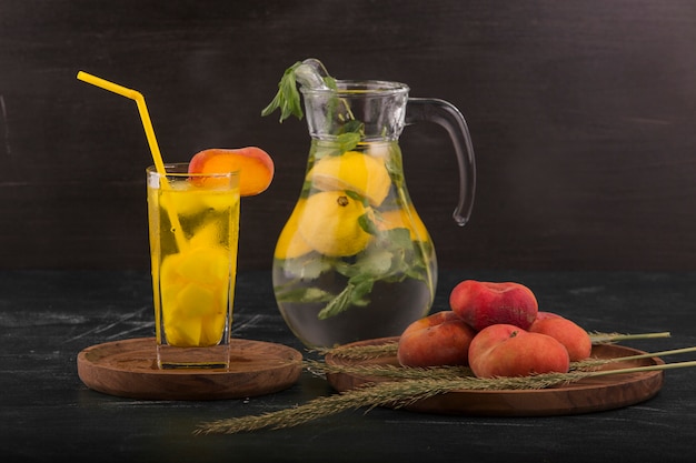 Pêches rouges avec un verre de jus et de limonade dans le pot