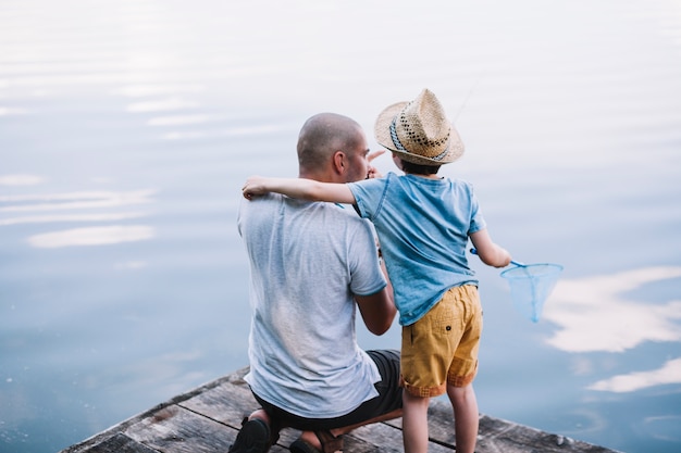 Pêcheur avec son fils tenant un filet de pêche près du lac