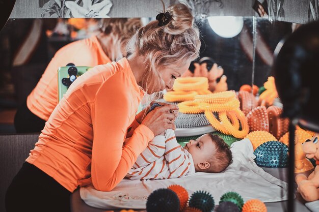 Une pégiatre expérimentée et diligente fait des exercices spéciaux pour un mignon petit bébé dans son armoire.