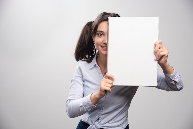 Peintre Brune Cachant Son Demi-visage Derrière Une Toile Blanche.