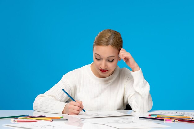 Peintre jolie jeune fille blonde peintre dessinant sur le papier avec un stylo bleu