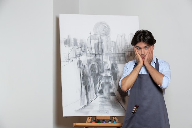 Peintre masculin stressé posant avec son studio de peinture dessin de fond blanc