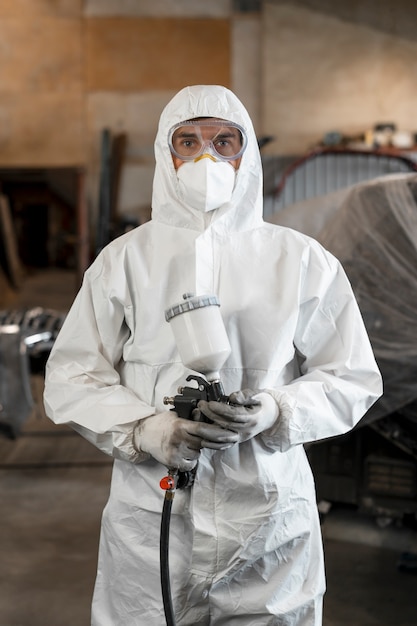 Photo gratuite peintre masculin vêtu d'un costume de matières dangereuses à l'intérieur d'un magasin de voitures