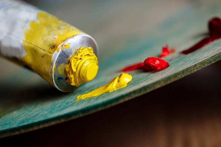Photo gratuit peintures à l'huile rouge et jaune sur palette sur mur en bois