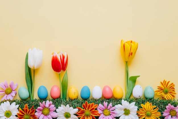 Pelouse créative avec des fleurs et des oeufs de Pâques