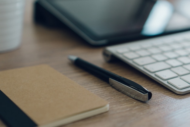 Pen à côté du clavier sur la table en bois