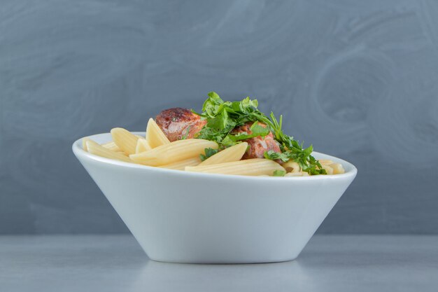 Penne au poulet rôti dans un bol blanc.