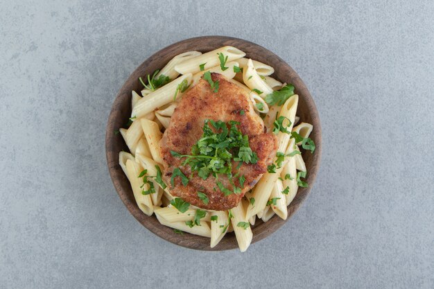 Penne au poulet rôti dans un bol en bois.