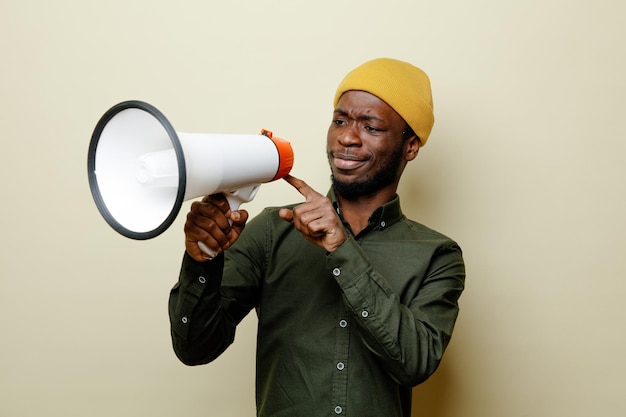 Photo gratuite penser jeune homme afro-américain en chapeau portant une chemise verte tenant et regardant le haut-parleur isolé sur fond blanc