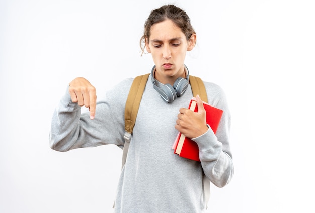 Penser regardant vers le bas un jeune étudiant portant un sac à dos avec un casque sur le cou tenant des livres pointe vers le bas