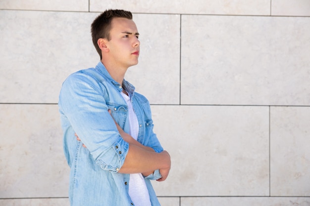 Pensive étudiant concentré guy avec bras croisés