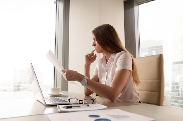 Pensive, femme d&#39;affaires, lecture, document, dans, bureau