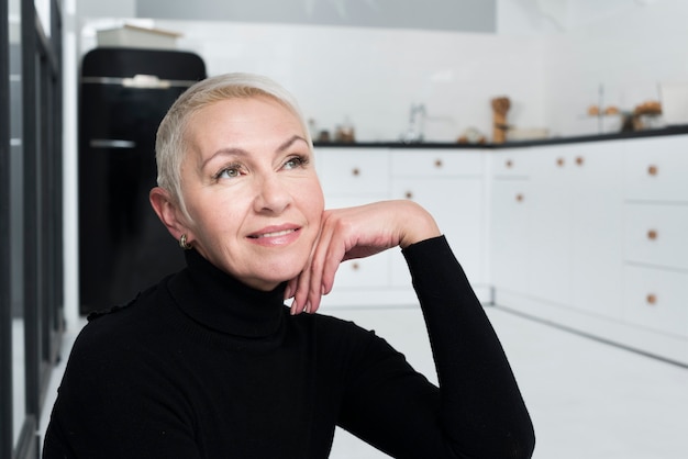 Pensive femme aînée posant dans la cuisine