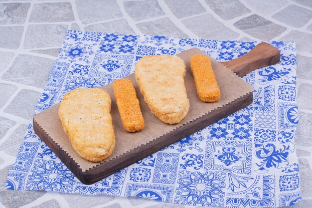 Pépites de poisson isolées sur une planche de bois.