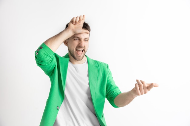 Les perdants rentrent chez eux. Portrait of happy guy montrant le signe du perdant sur le front et souriant à cause de la victoire et de rire sur fond gris