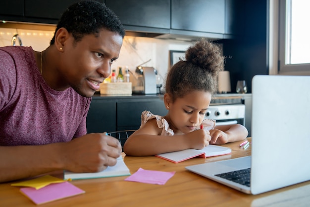 Père aidant et soutenant sa fille avec l'école en ligne tout en restant à la maison