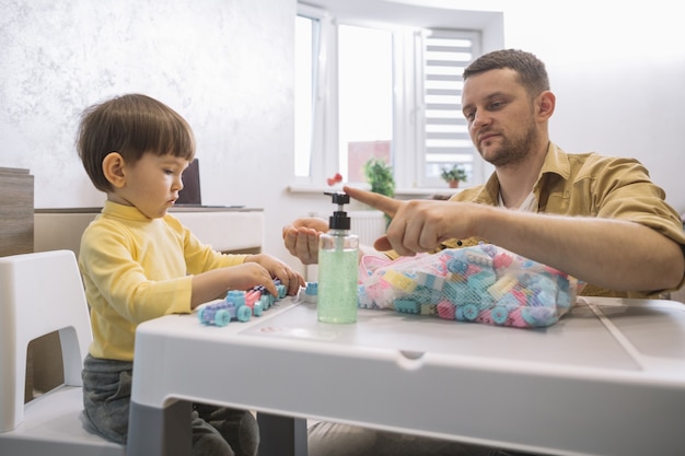 Père à l'aide de désinfectant pour les mains sur ses mains