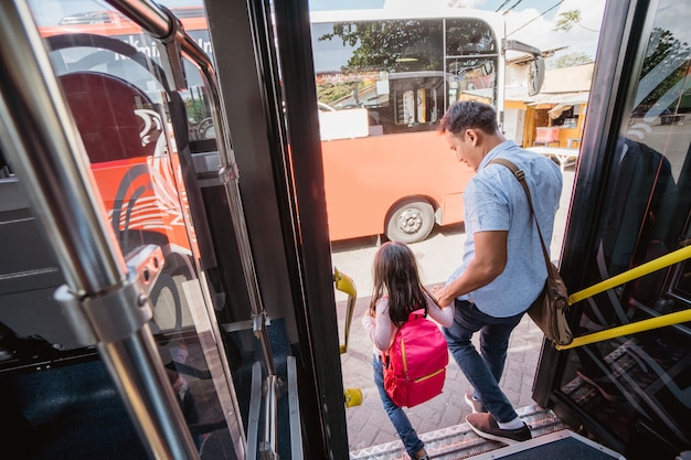 Père asiatique emmenant sa fille à l'école en empruntant les transports publics en bus