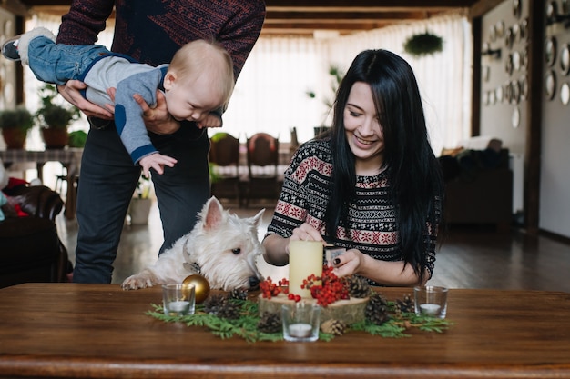 Père avec bébé dans les bras pendant que la mère allume une bougie