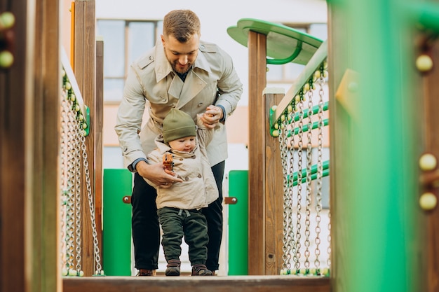 Père avec bébé sur terrain de jeu s'amusant