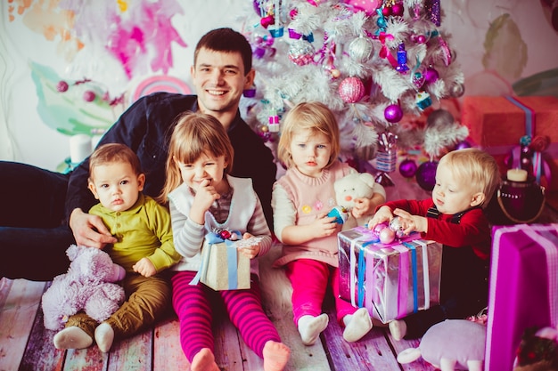 Le père embrasse ses enfants près de l&#39;arbre de Noël