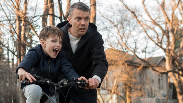 Photo gratuite père enseigne à son fils comment faire du vélo