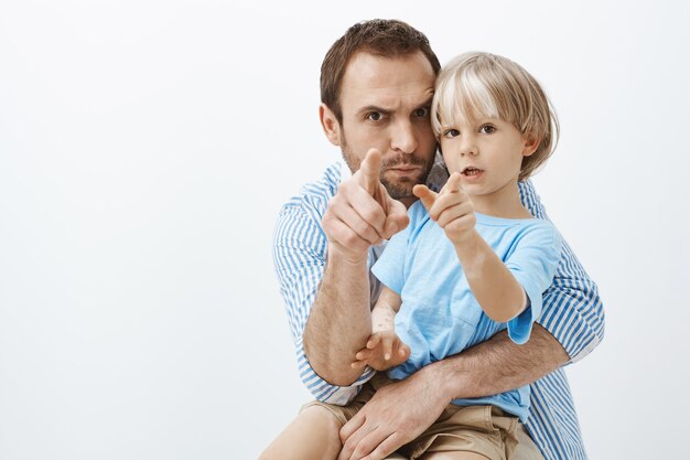 Père européen attentionné drôle, tenant et étreignant un petit fils mignon avec vitiligo, pointant, fronçant les sourcils et faisant des grimaces