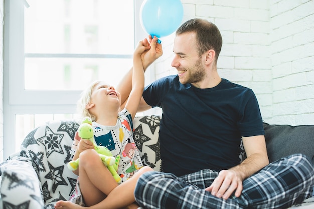 Père et fille ayant un grand temps avec un ballon bleu