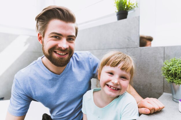 Père et fille avec de la crème sur le nez