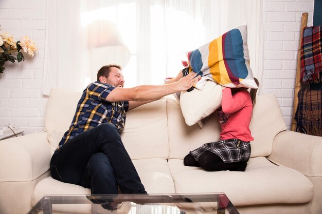 Père et fille jouent avec des coussins